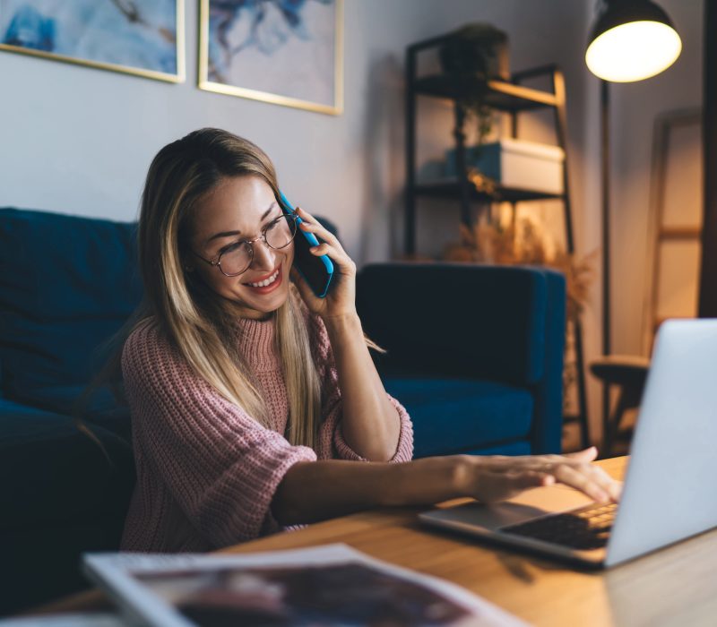 European,Girl,In,Glasses,Talking,On,Smartphone,And,Using,Laptop